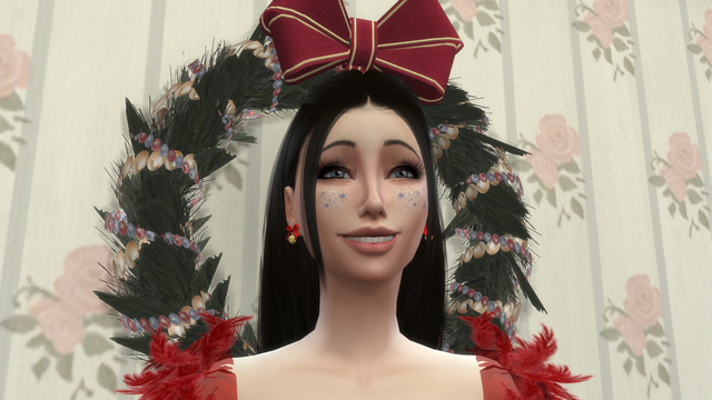 Sim souriante aux longs cheveux noirs, coiffée d’un grand nœud rouge, devant une couronne de Noël