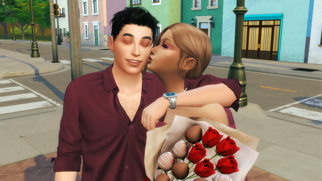 Couple de Sims habillés en bordeaux, elle l’embrasse sur la joue ; au premier plan, un bouquet de roses rouges et de fraises au chocolat